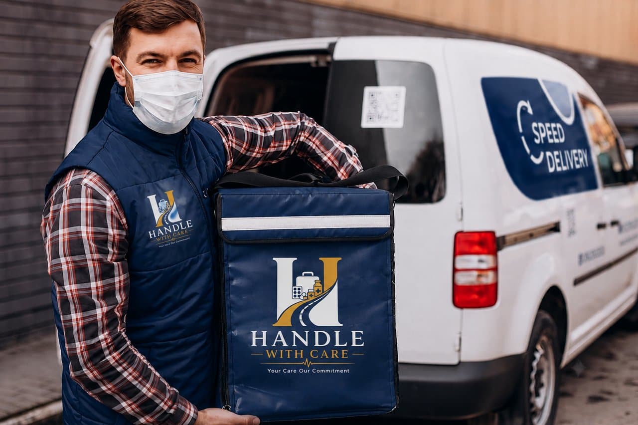 Professional courier in a branded Handle With Care vest beside a delivery van